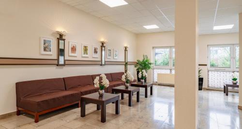 a waiting room with a couch and two tables at PLAZA INN Karlsruhe Nord in Karlsruhe