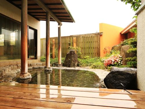 a pool of water in a yard with a house at Ryokan Kamomeso in Sado