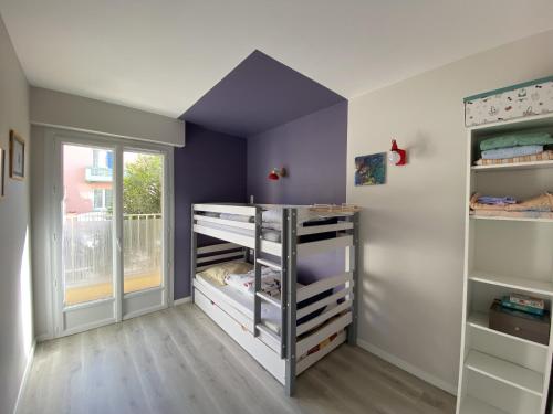 une chambre d'enfant avec des murs et des étagères violets dans l'établissement Appartement Le Leon, à La Rudelière