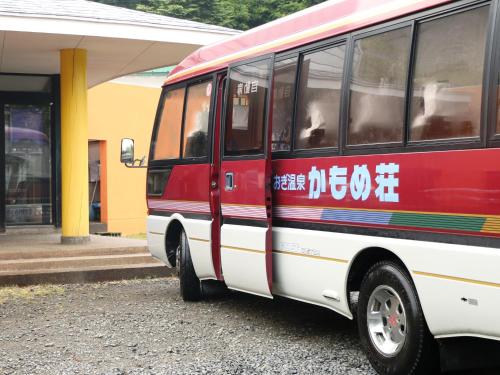 a red and white bus parked next to a building at Ryokan Kamomeso in Sado