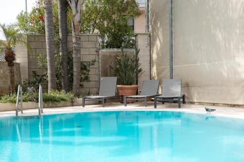 a blue swimming pool with two chairs next to a building at UNICO Albatres Palace Salento by Life Resorts in San Vito dei Normanni