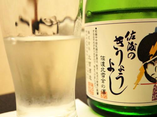 a bottle of sake and a glass of water at Ryokan Kamomeso in Sado
