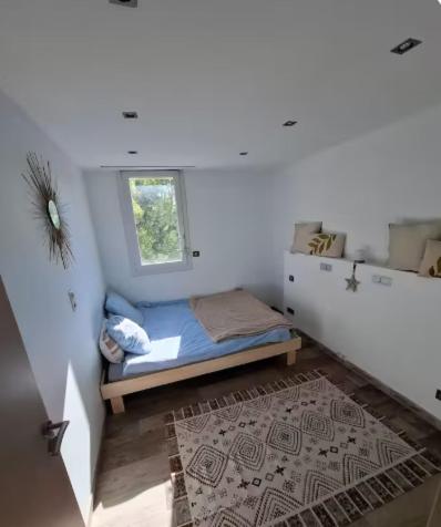 Cette petite chambre blanche dispose d'un lit et d'une fenêtre. dans l'établissement Le Cap Inné, à Draguignan