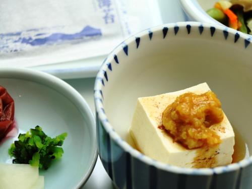 a blue and white bowl with a piece of food in it at Ryokan Kamomeso in Sado