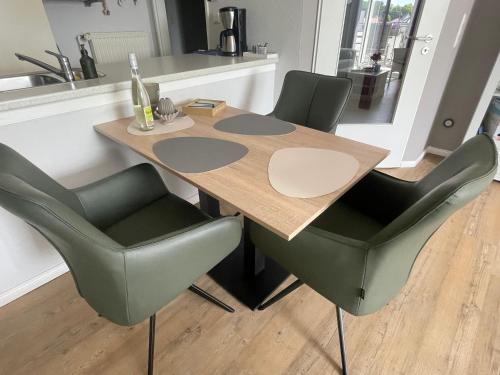 ein Holztisch mit vier grünen Stühlen um ihn herum in der Unterkunft "Haus Atlantic" - Wohnung "StrandGut" in Grömitz
