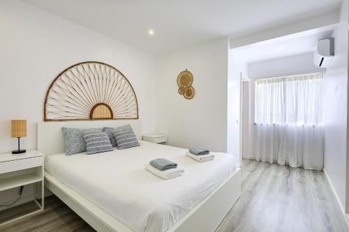 une chambre blanche avec un grand lit et une fenêtre dans l'établissement Casa Baleeira - Modern apartment with Seaview, à Armação de Pêra