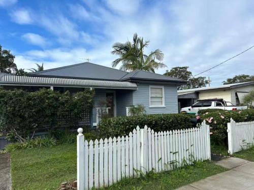 a white picket fence in front of a house at Spacious Stylish Coastal Escape in Tuncurry