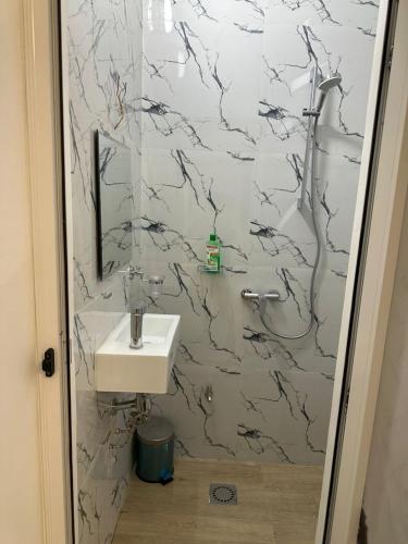 a bathroom with a sink and a marble wall at Tinou Apparts zac Mbao in Dakar