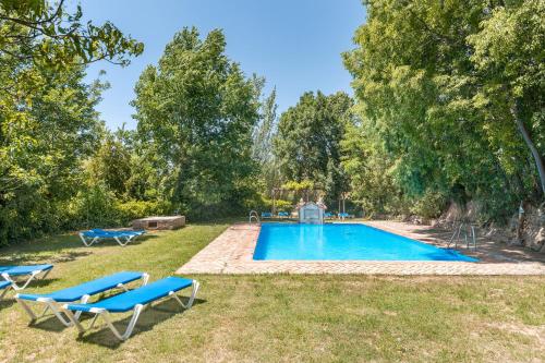 a swimming pool with two blue lounge chairs in a yard at El Cobertizo in La Zubia