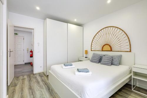 - une chambre blanche avec un grand lit blanc et des oreillers bleus dans l'établissement Casa Baleeira - Modern apartment with Seaview, à Armação de Pêra