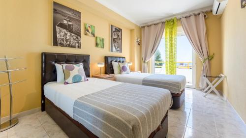 two beds in a room with yellow walls at Star Paradise in Armação de Pêra