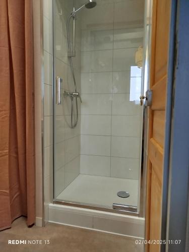 une douche dans une salle de bain avec une porte vitrée dans l'établissement Le Sarciron 152, à Le Mont-Dore