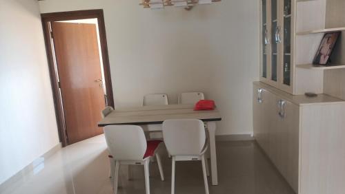 Una mesa de comedor con sillas blancas y un espejo. en Roadshow housing apartment budhanilkantha, en Bākhri Kharka