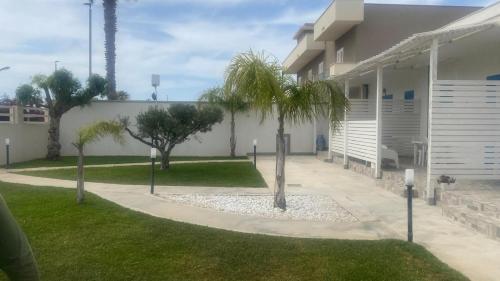 a house with palm trees next to a sidewalk at Casa Vacanze-Le stanze di Eolo in Marsala