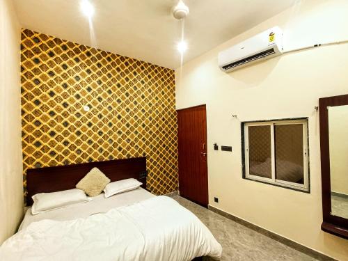 a bedroom with a bed and a yellow wall at Hotel Ajanta in Pushkar