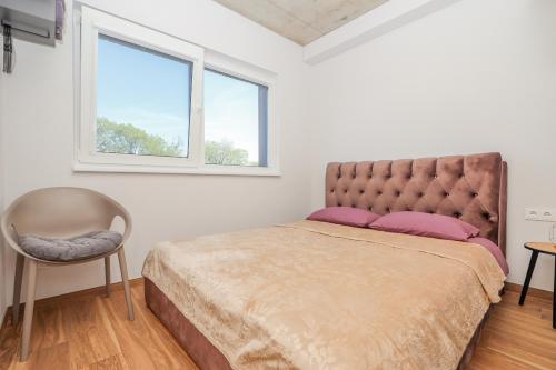 a bedroom with a bed and a chair and a window at Monciskes Terrace Apartment in Palanga
