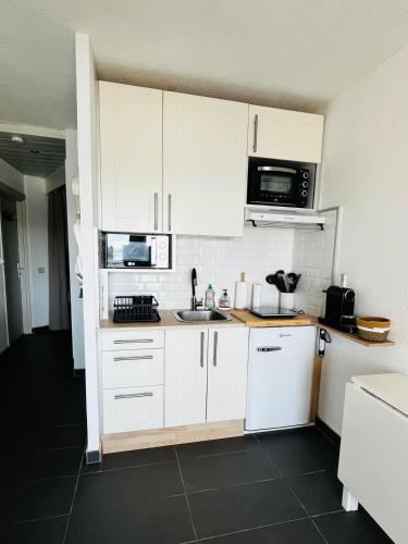une cuisine avec des armoires blanches et un évier dans l'établissement Nouveau, studio Port de Carnon 4 personnes, à Carnon-Plage
