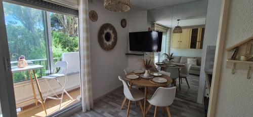 une salle à manger avec une table, des chaises et une télévision dans l'établissement Studio 4p, cozy, 100m mer , piscine, au pied des commerces, à La Grande Motte