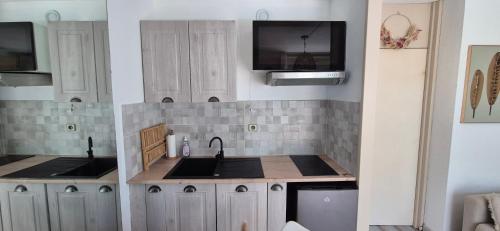 Il comprend une cuisine avec un évier et une télévision murale. dans l'établissement Studio 4p, cozy, 100m mer , piscine, au pied des commerces, à La Grande Motte