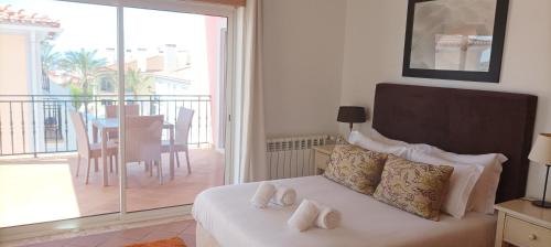 a bedroom with a bed and a balcony with a table at Esplendor beiramar refúgio na Praia del Rey B9 in Amoreira