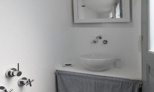 a white bathroom with a sink and a mirror at Koukios Cell in Serifos Chora