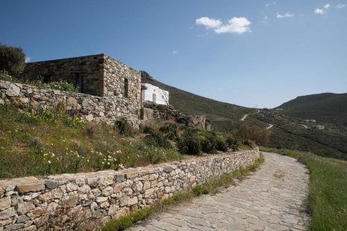 a stone wall on a hill with a road at Koukios Cell in Serifos Chora