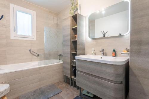 une salle de bain avec un lavabo, une baignoire et un miroir dans l'établissement Villa de l'artiste Andrea, à Fréjus