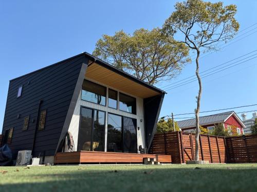 a black house with large windows and a tree at 一棟貸切,新築,広いドッグランの庭付き,ペット可,海徒歩10分,bbq,美味しい肉セット注文可 in Jōnouchi
