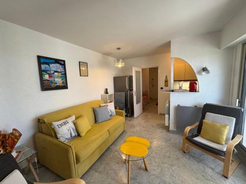 un salon avec un canapé jaune et une cuisine dans l'établissement LE MAGALI , Vue Mer , Clim , Parking, à Villeneuve-Loubet