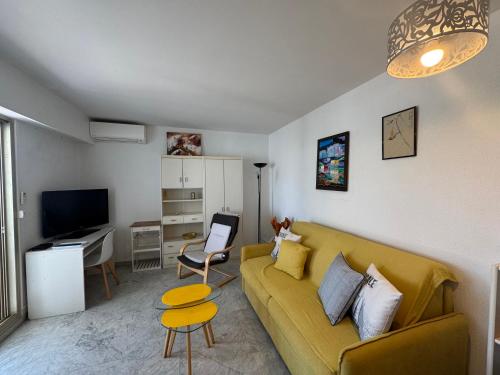 un salon avec un canapé jaune et une télévision dans l'établissement LE MAGALI , Vue Mer , Clim , Parking, à Villeneuve-Loubet