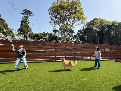 two men playing with a dog in a yard at 一棟貸切,新築,広いドッグランの庭付き,ペット可,海徒歩10分,bbq,美味しい肉セット注文可 in Jōnouchi