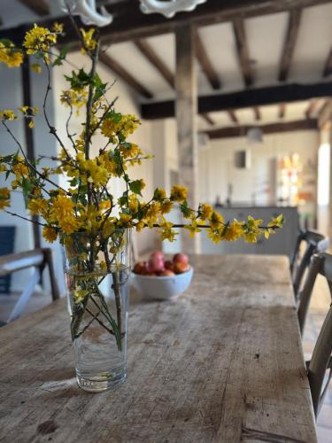 a vase with yellow flowers sitting on a wooden table at Domaine la Boulinière - Le Faisan in Journet