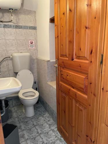 a bathroom with a toilet and a sink and a wooden door at Port view house in Poros