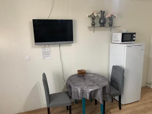 une table et des chaises avec une télévision murale dans l'établissement Le Petit Cap Normand - Calme et Reposant, à Grandcamp-Maisy