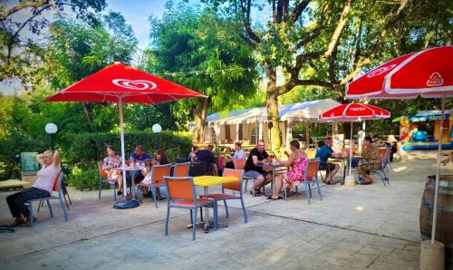 Un groupe de personnes assises à des tables sous des parasols dans l'établissement Emplacement tente, caravane 120 m2, à Chauzon