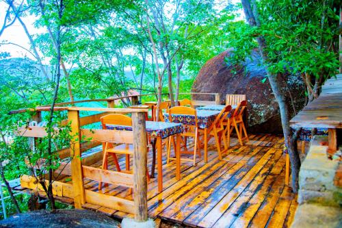 une terrasse en bois avec une table et des chaises dessus dans l'établissement Aika Sunrise - Your Home in the Hills, à Iringa