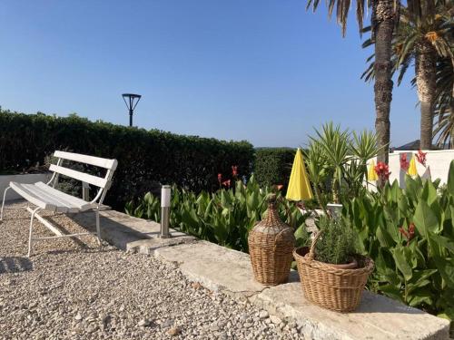 a white chair and some plants and a bench at Ruvo Apartman 5 in Orebić