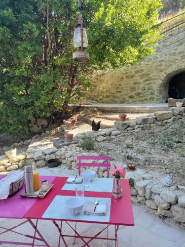 une table de pique-nique rouge avec des assiettes et des fleurs dessus dans l'établissement Moulin de Bonfilhon, à Cornillon-Confoux