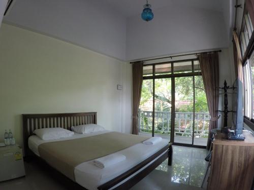 a bedroom with a bed and a large window at The Old Palace Resort Klong Sa Bua in Phra Nakhon Si Ayutthaya