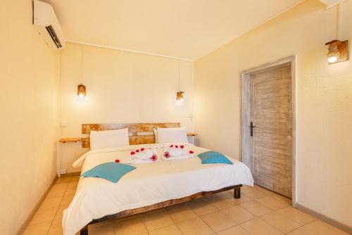 a bedroom with a bed with white sheets and flowers on it at Cocotiers Hotel – Mauritius in Port Louis