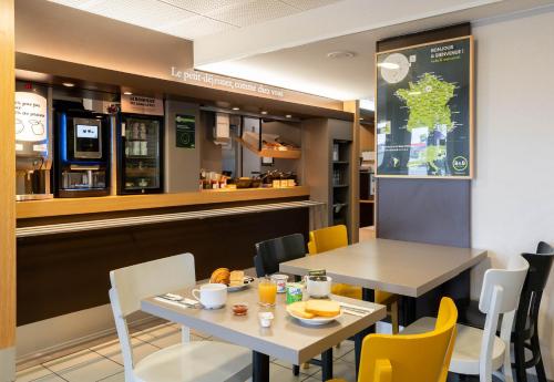 un restaurant avec deux tables et des chaises ainsi qu'un comptoir dans l'établissement B&B HOTEL Saint-Nazaire Trignac, à Trignac