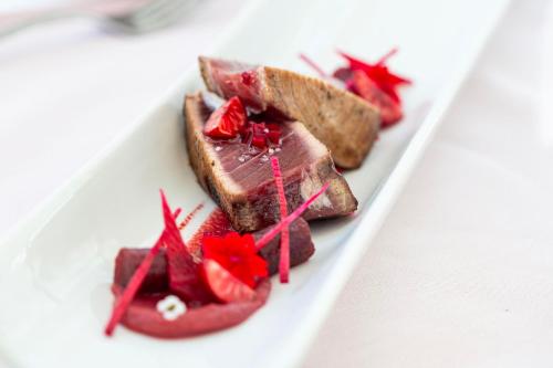 a plate of food with meat and strawberries on it at Grand Hôtel Du Lido in Argelès-sur-Mer
