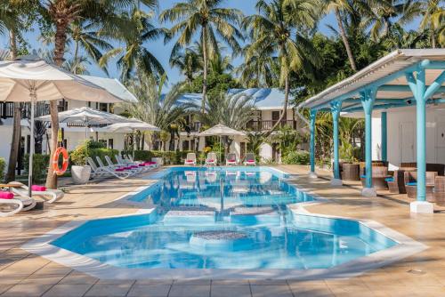 a pool with chairs and umbrellas at a resort at Cocotiers Hotel – Mauritius in Port Louis