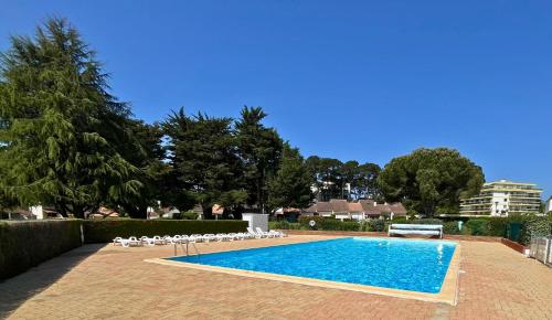 a swimming pool with white chairs at Casa Otarie avec piscine et terrasse -Proxi plage, port, gare in Pornic