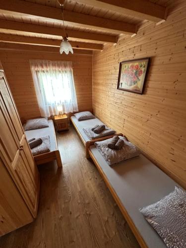 a room with two beds in a wooden wall at Domki u Polaka in Uherce Mineralne (7)