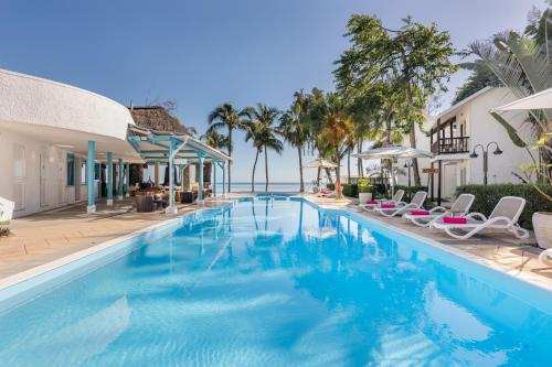 a swimming pool with chairs and the ocean in the background at Cocotiers Hotel – Mauritius in Port Louis