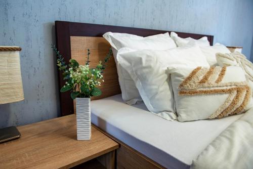 a bed with white pillows and a vase on a table at Alba in Tryavna