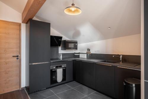 - une cuisine avec des placards noirs et un évier dans l'établissement Apartment Ascar Alpe d'Huez - by EMERALD STAY, à Huez