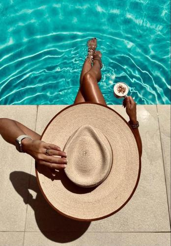 a woman laying in the swimming pool with a hat at Nomas Living in Kalamaki