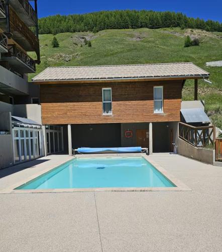 une maison avec piscine devant un immeuble dans l'établissement Appartement 35 m2 4p avec piscine chauffée la foux d Allos, à La Foux d'Allos